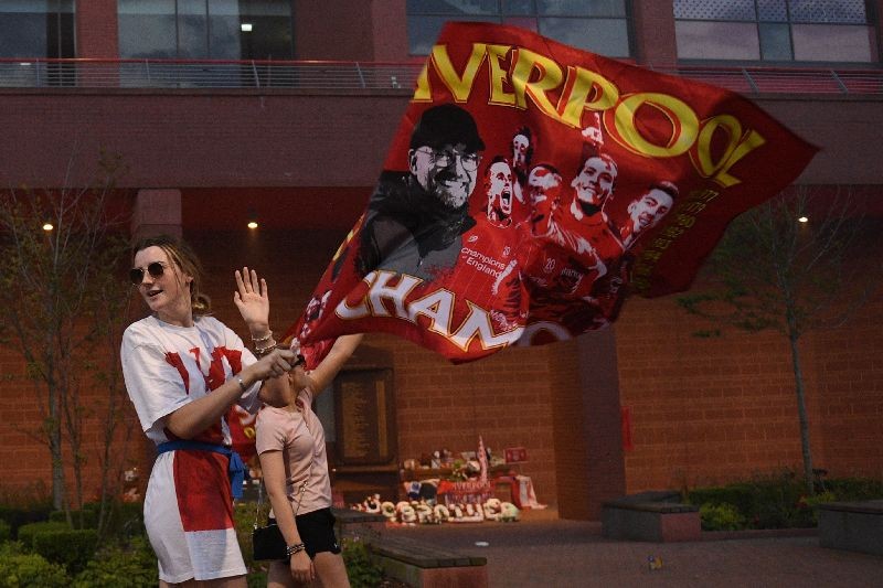 Fans celebrate Liverpool winning the championship title of the English Premier League following Chelsea's 2-1 victory over Manchester City, outside Anfield stadium in Liverpool, north west England . (Photo by Oli Scarff/AFP Photo)